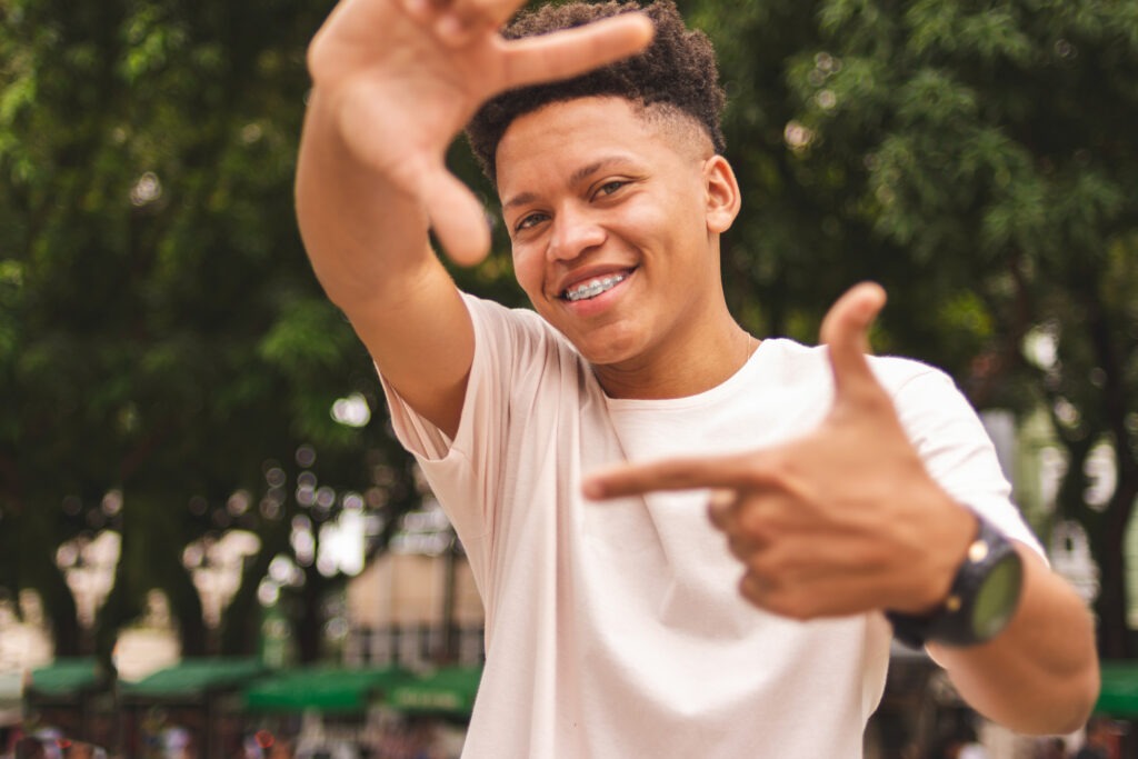 Portrait of a brazilian guy doing frame with fingers looking at you Orthodontist Near Me