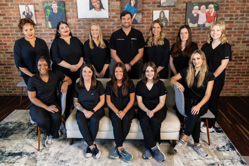 Team of orthodontic professionals at Johnson Orthodontics in black scrubs, posing together in a welcoming office setting, emphasizing personalized care and community support in Huntsville and Hampton Cove.